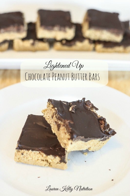 Picture of lined up chocolate peanut butter bars in the background and two chocolate peanut butter bars in the front on a white plate.