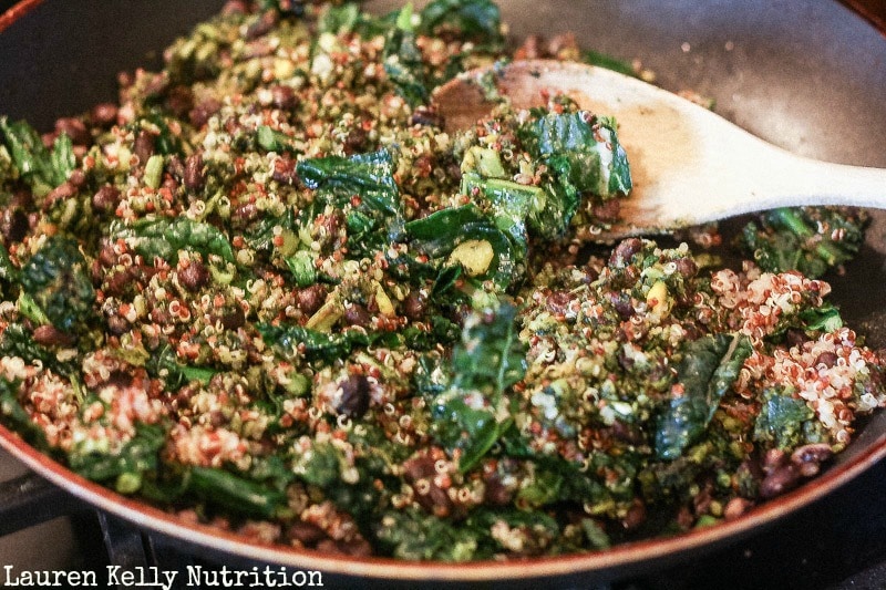 Kale and Quinoa Stuffing for peppers in a skillet with a wooden spoon.