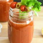 Homemade bloody mary in mason jar with celery stick coming out.