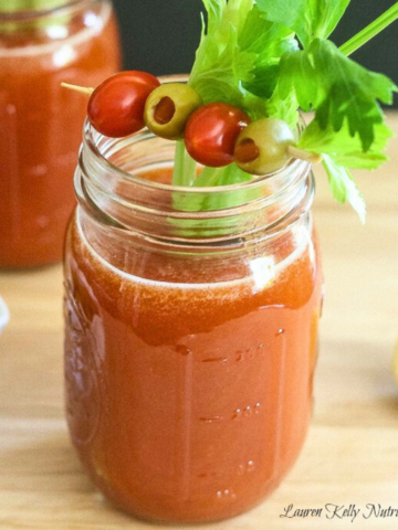Homemade bloody mary in mason jar with celery stick coming out.