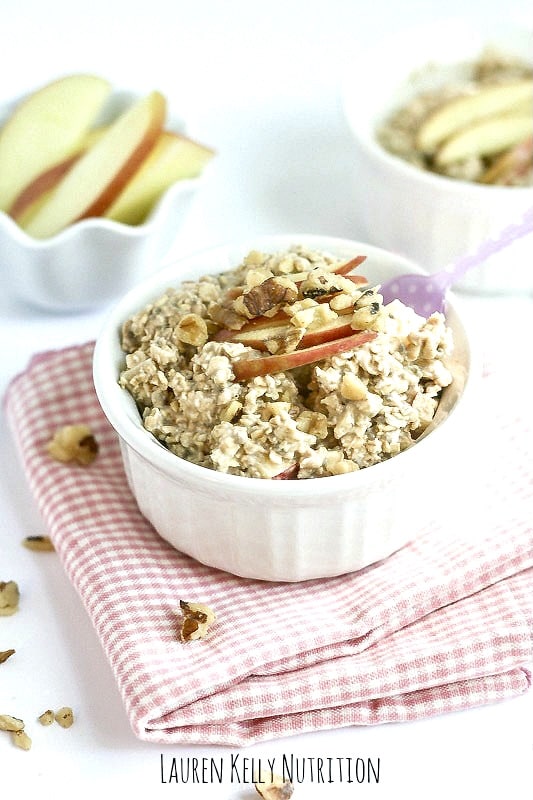 Apple Pie Overnight Oats in a white bowl with sliced apples on top.