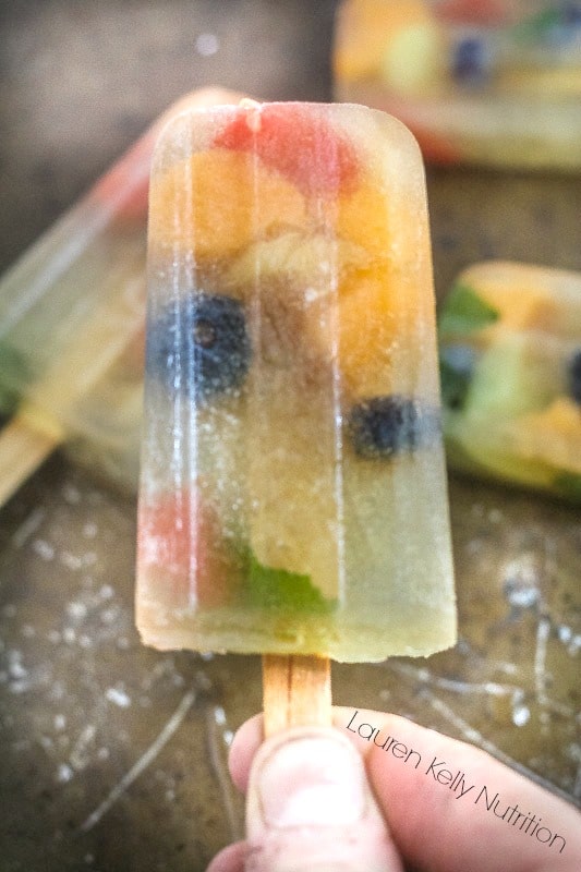 Close up picture of someone holding one sangria popsicle with other popsicles in the background.