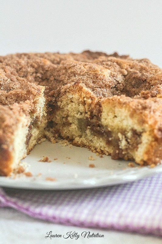 Coffee cake on a white plate with a slice cut out of it.