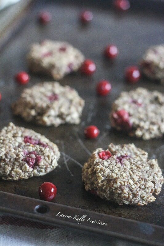 Cranberry Orange Breakfast Cookies on a dark baking sheet with scattered cranberries on it.