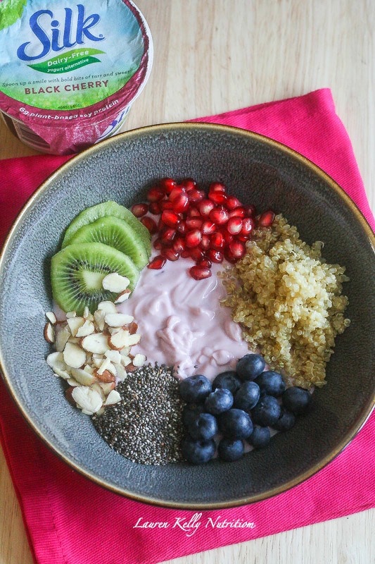 Healthy Breakfast Bowl in a dark bowl with all ingredients separated and yogurt in the middle.