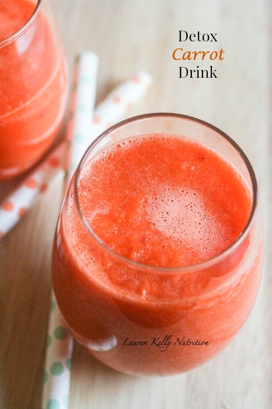 Detox carrot drink in a clear glass.