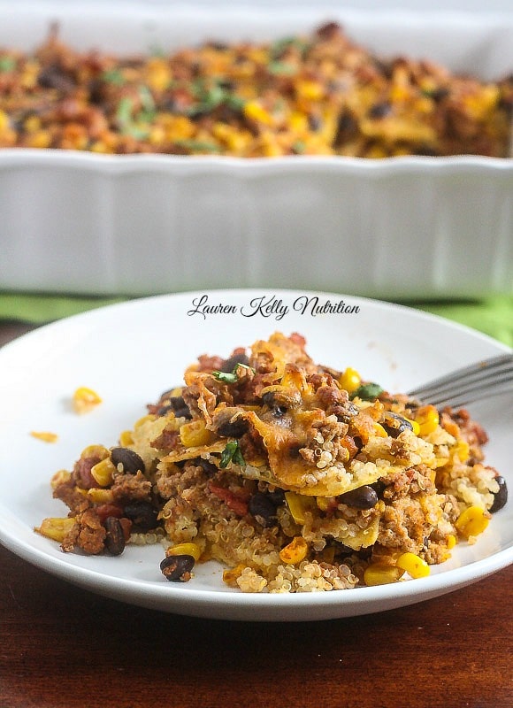 A slice of Mexican Quinoa Lasagna on  white plate with casserole dish behind it.