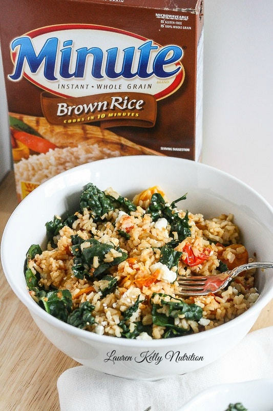 Close up on brown rice salad in a white bowl.