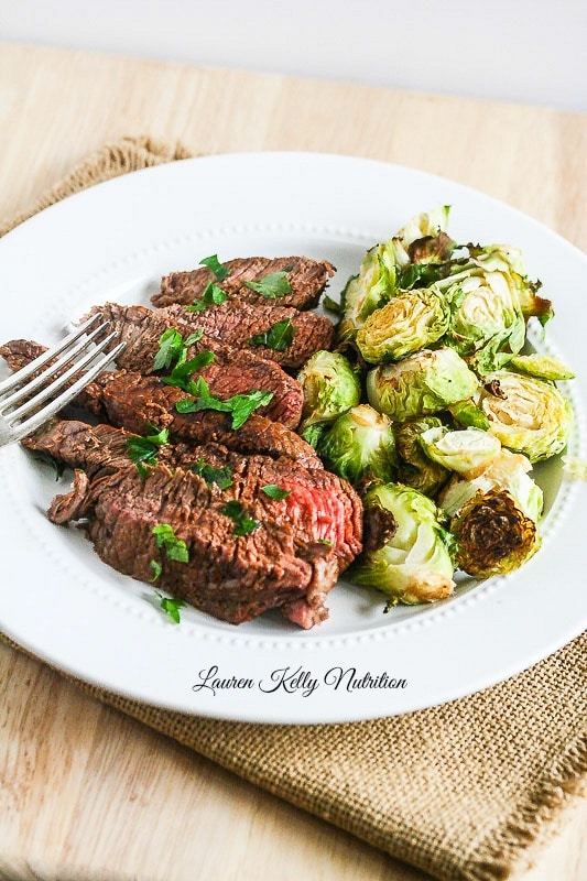 Filet on a white plate with brussels sprouts.