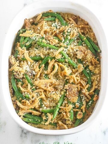 Overhead picture of cooked green bean casserole in a white baking dish.