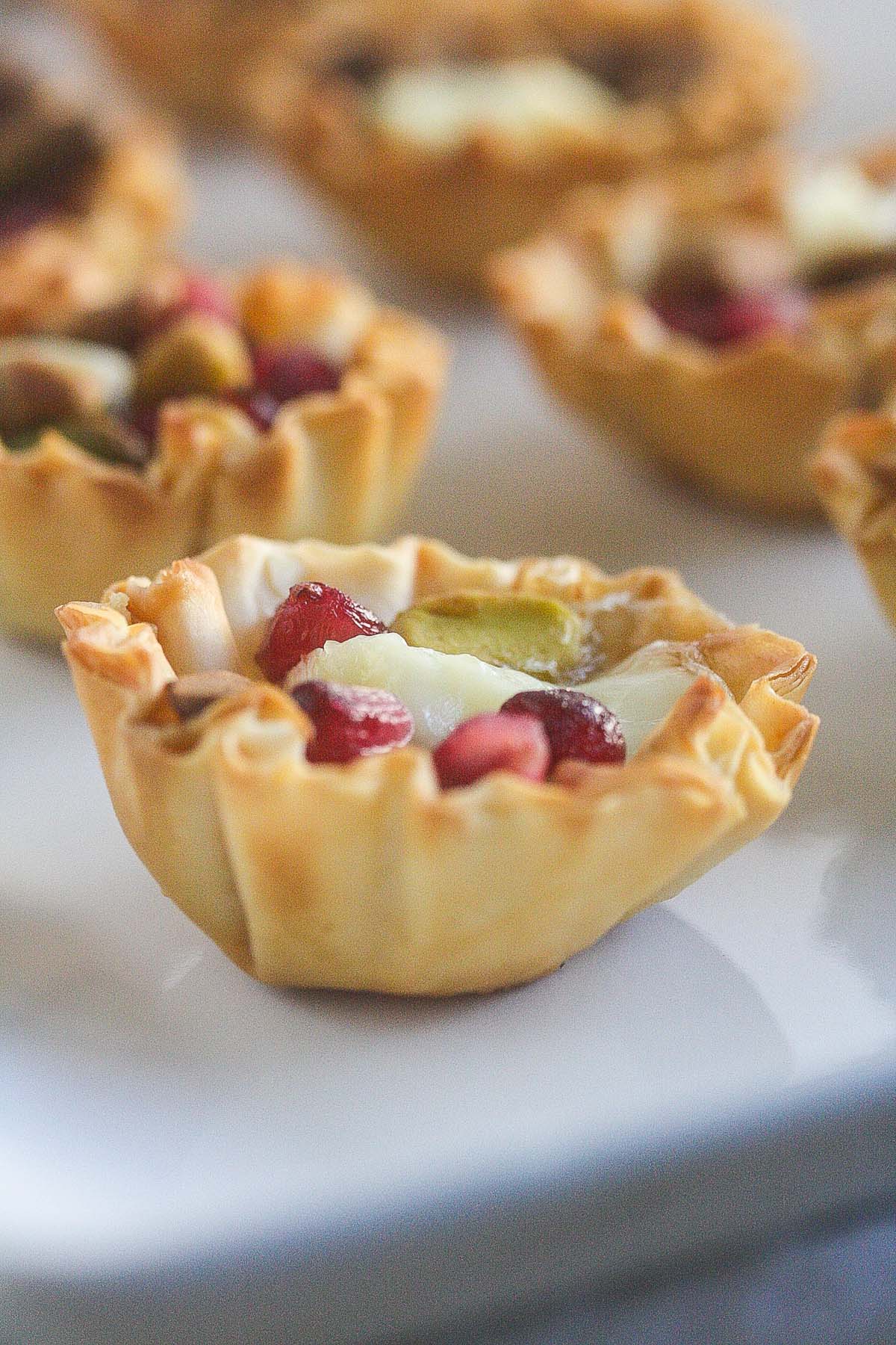 Close up of Pomegranate Brie Phyllo Cups on a white background.