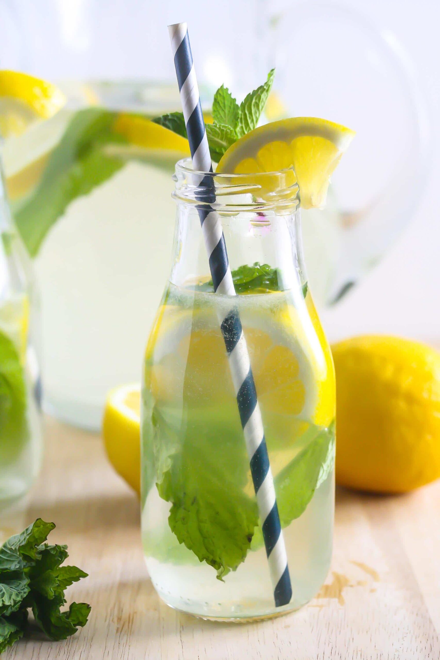 Coconut Water Ginger Lemonade in a clear jar with a blue and white stripe straw and lemon on top.
