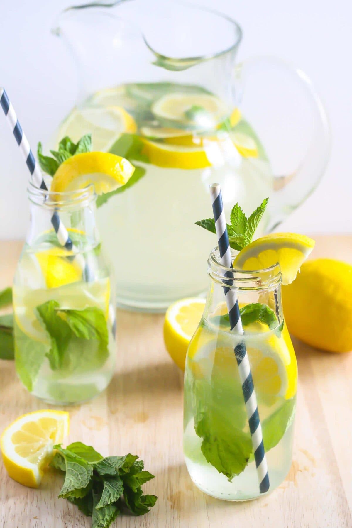 Coconut Water Ginger Lemonade in two clear tall glasses with blue and white striped straw and pitcher in the back.