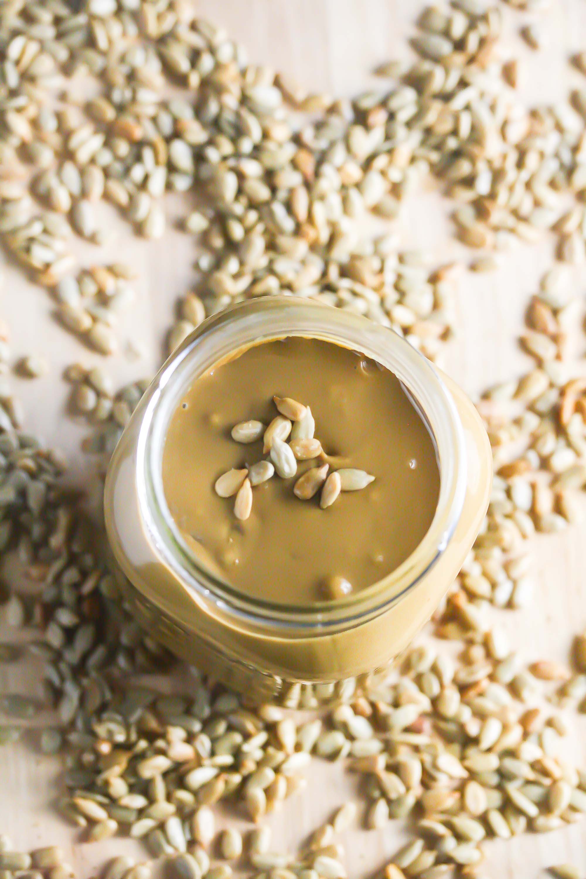 Overhead picture of Homemade Sunflower Seed Butter in a jar with scattered sunflower seeds around it.