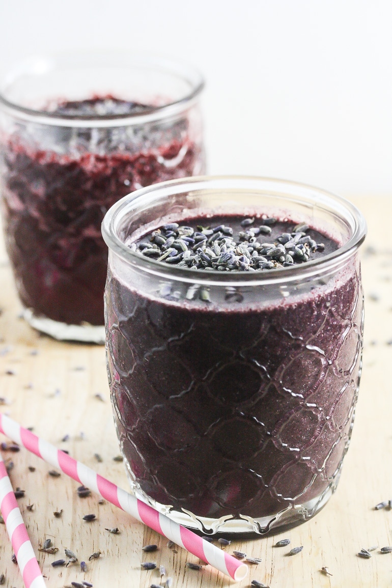 Blueberry Lavender Smoothie in a clear glass with lavender on top.