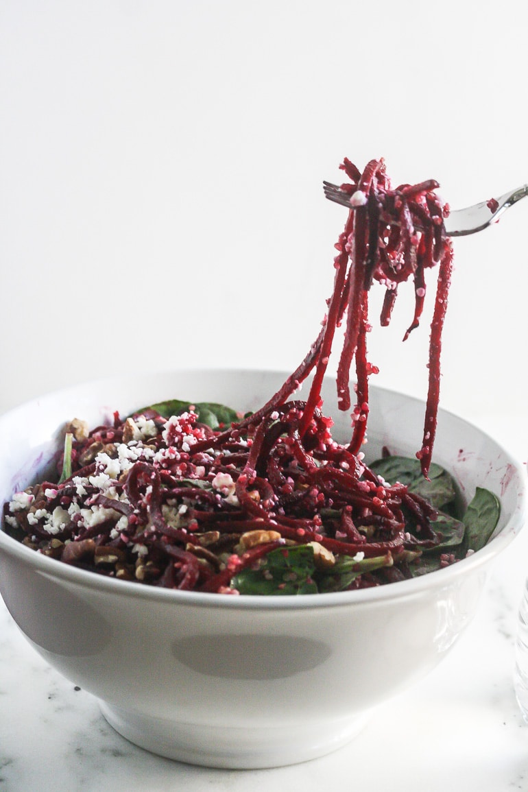 Beet Quinoa Salad in a white bowl with strands of beets on a fork.