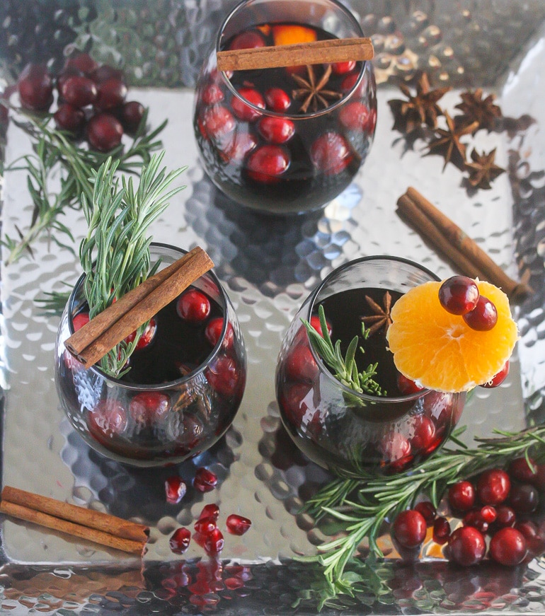 Overhead view of mulled wine in clear glass wine glasses on a silver tray.