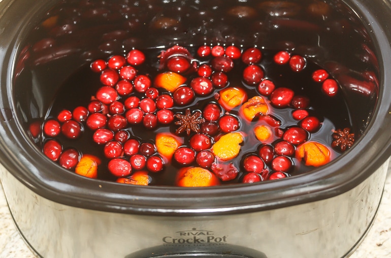 Mulled wine in a slow cooker with cranberries and orange.