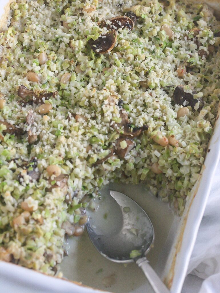 Broccoli cauliflower rice casserole in a white baking dish with a spoon in it.