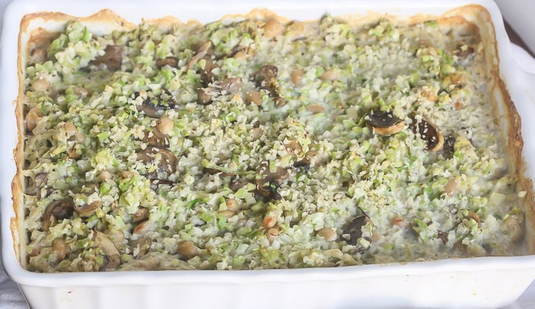 Broccoli cauliflower rice casserole pictures horizontally in a white baking dish.