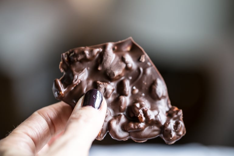 Handing holding a piece of Low Carb Keto Salted Pecan Dark Chocolate.