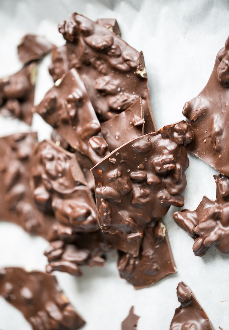 Pieces of Salted Pecan Dark Chocolate Bark on a white background.