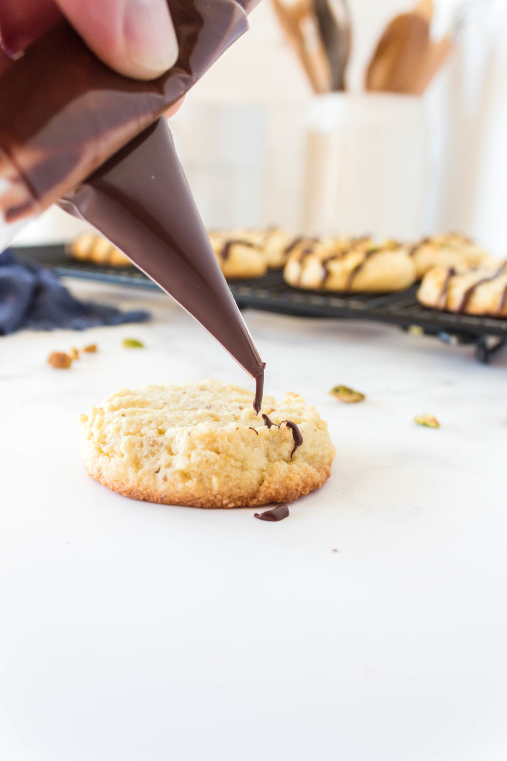 Picture of one keto butter cookie with chocolate being drizzled on top.