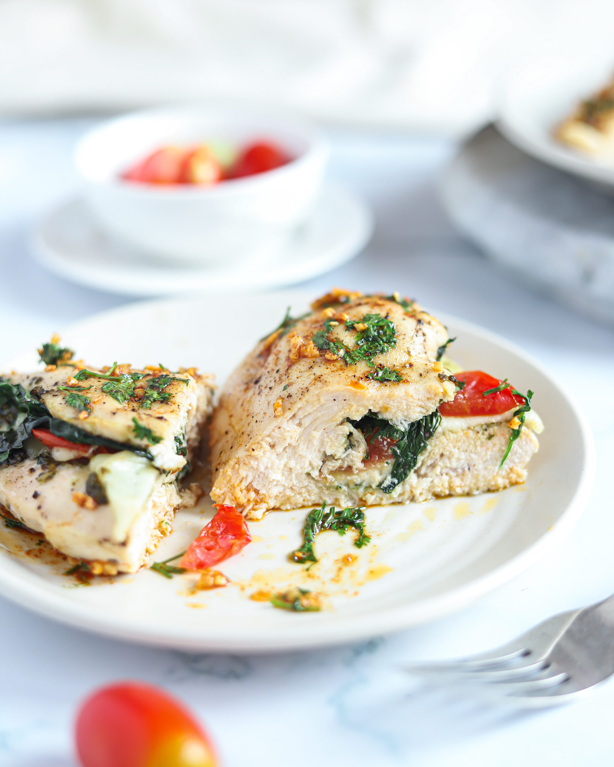 Cheesy Pesto Spinach Stuffed Chicken Breasts sliced in half on a. white plate.