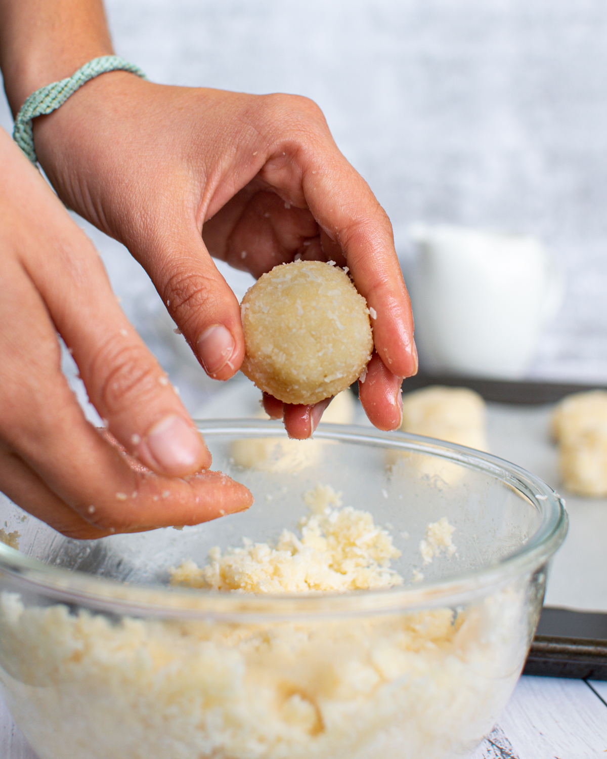 Picture of dough in a medium glass bowl with hands rolling dough into a ball.