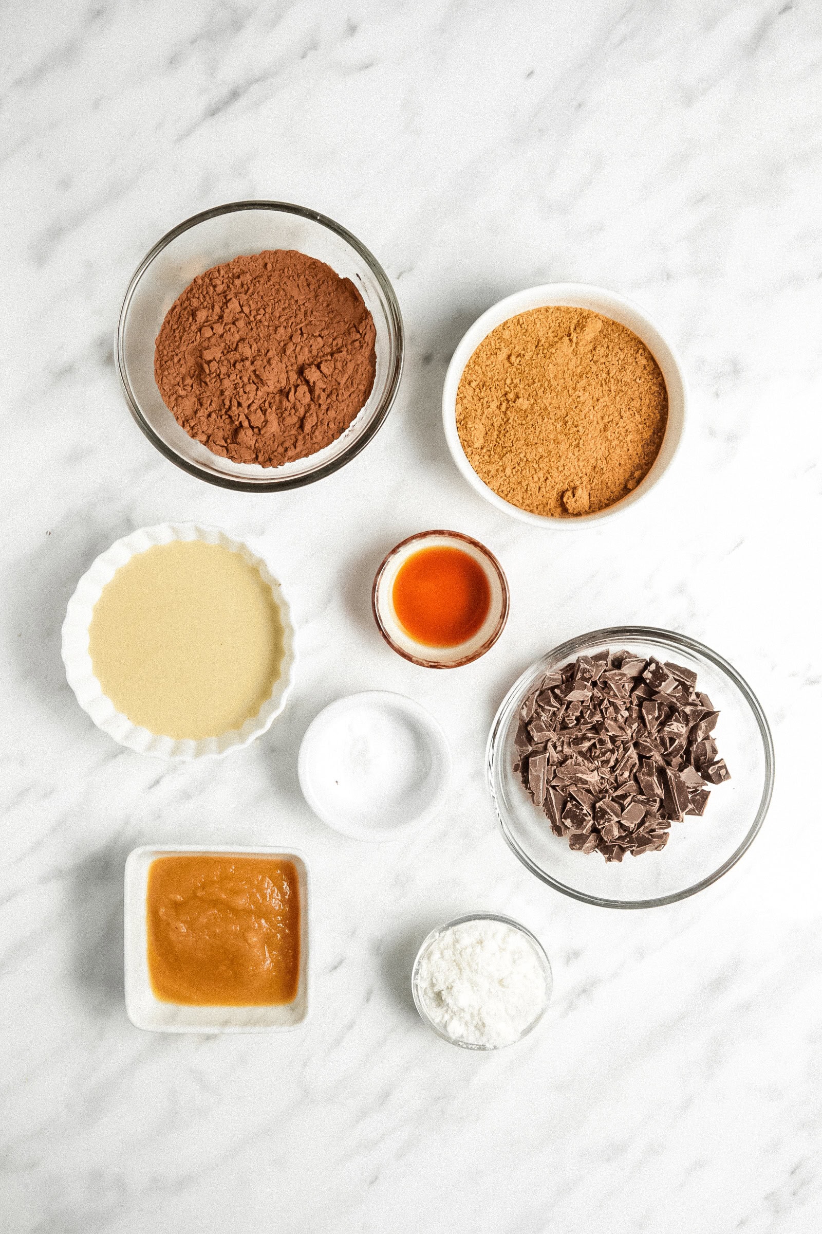 Picture of all 8 ingredients in small bowls on a marble counter.