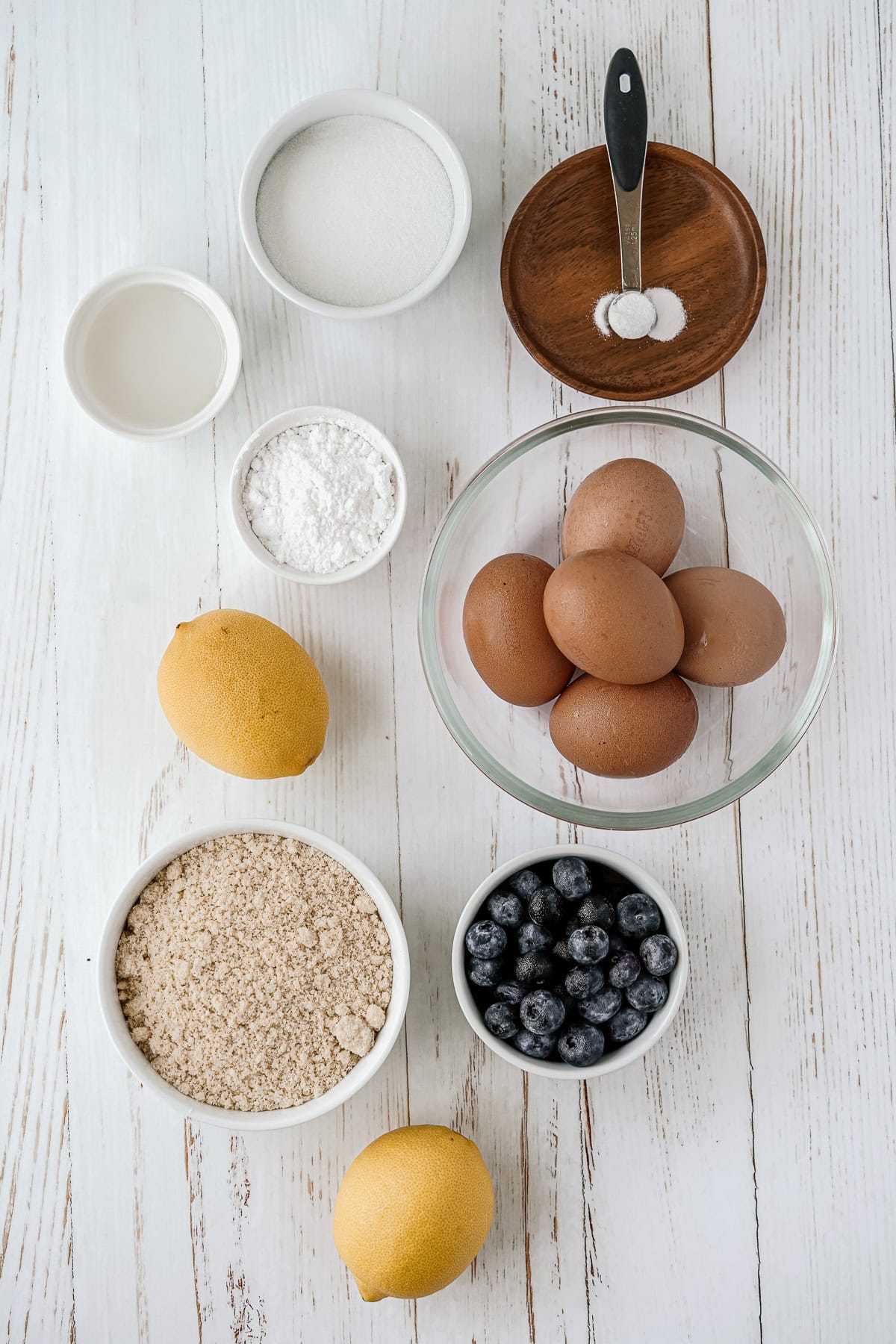 Overhead picture of all of the separate ingredients on a background, some in small white bowls,  small wooden plates and small glass bowls.