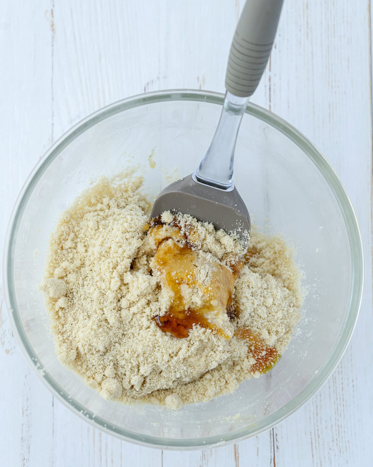 Overhead picture of ingredients in a glass bowl with a metal spoon inside.