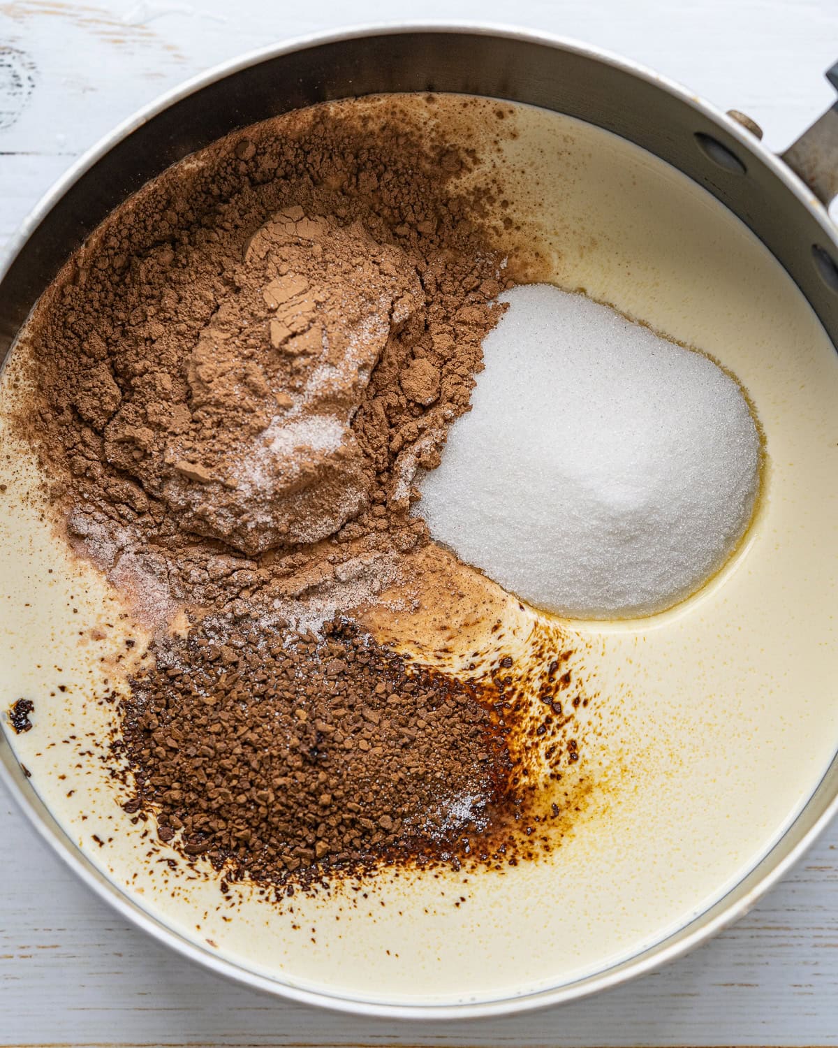 Ingredients for chocolate Panna Cotta in a large saucepan with some unmixed and laying on top.