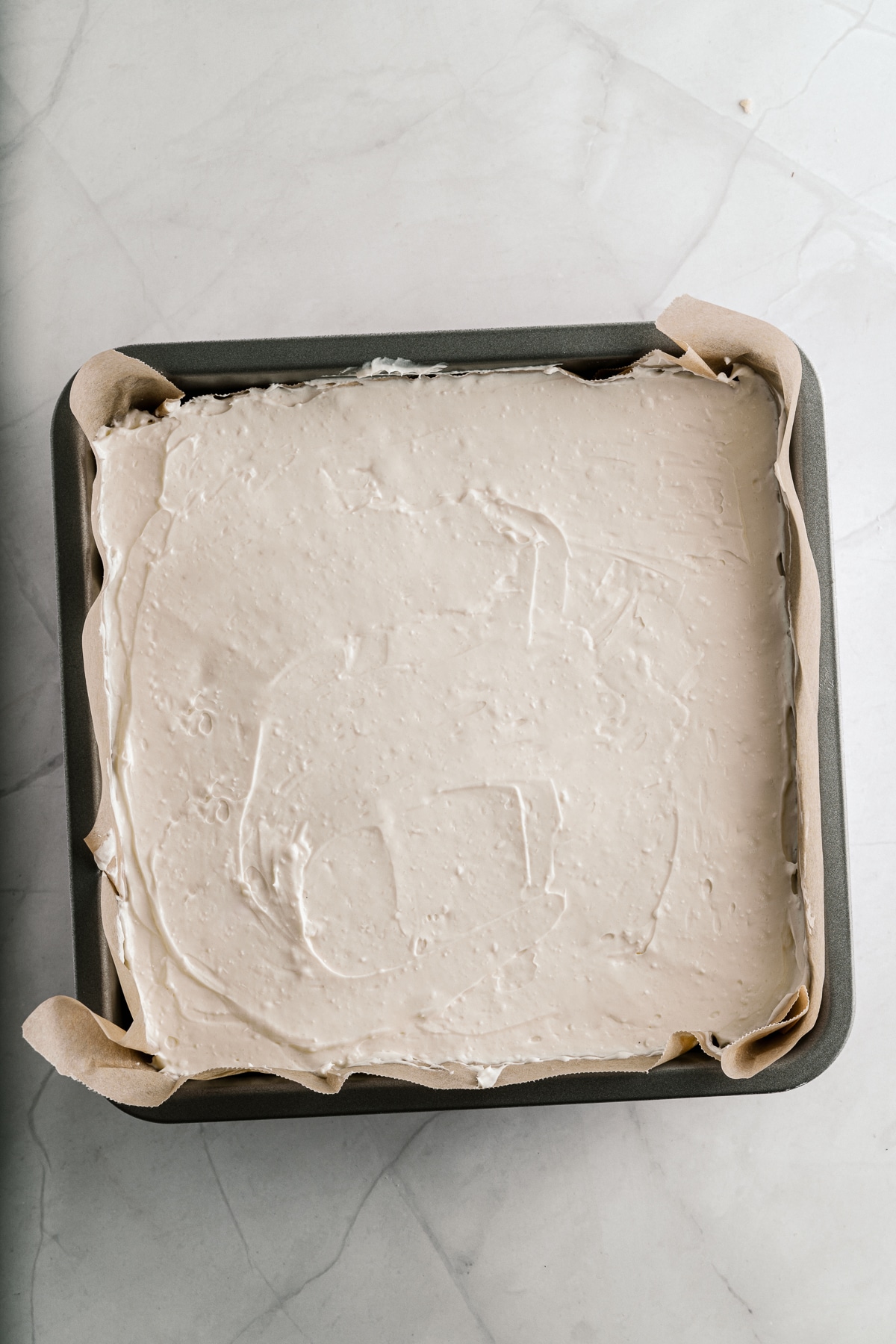 Overhead picture of cheesecake layer in a baking pan.