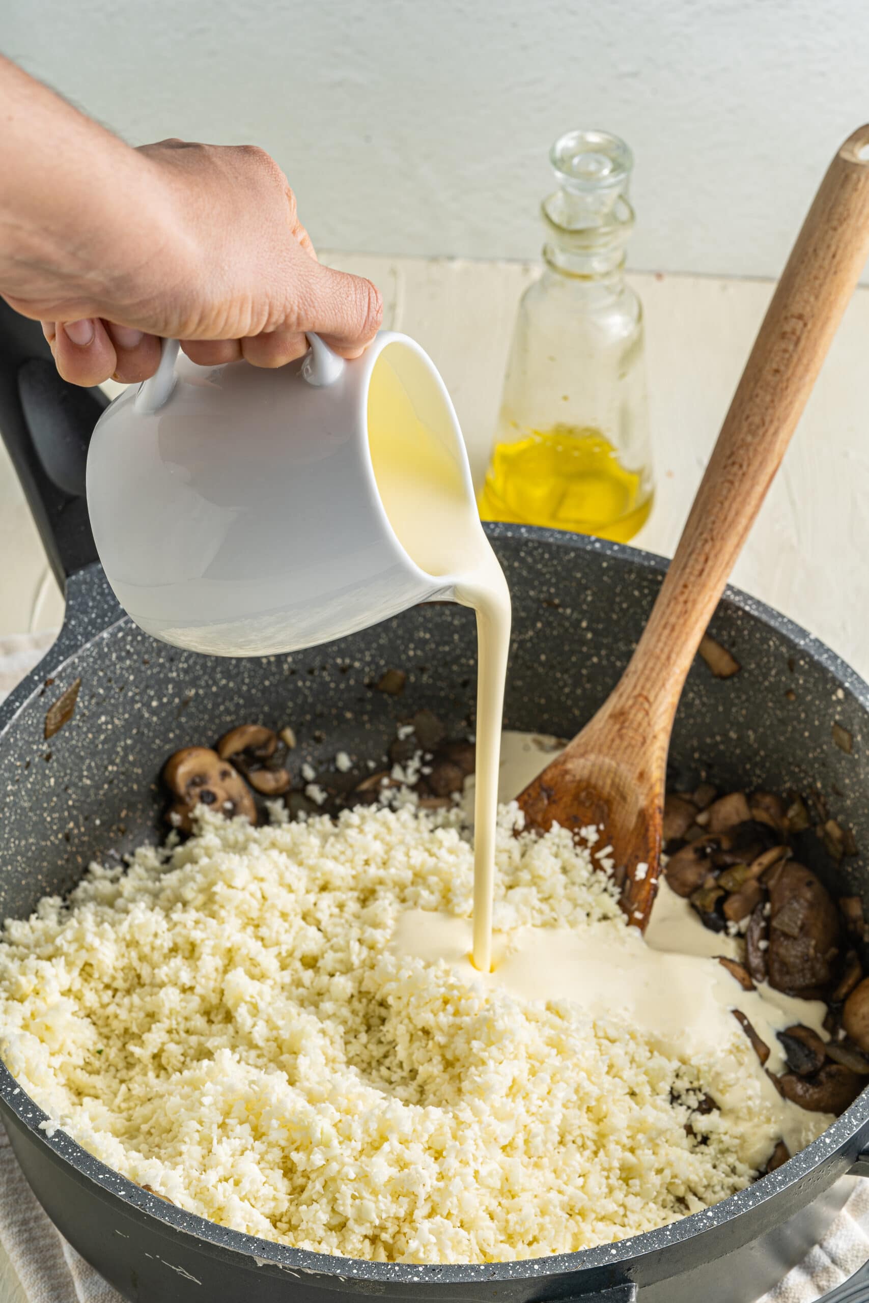 Picture of cream pouring into the pan with mushrooms and cauliflower rice.