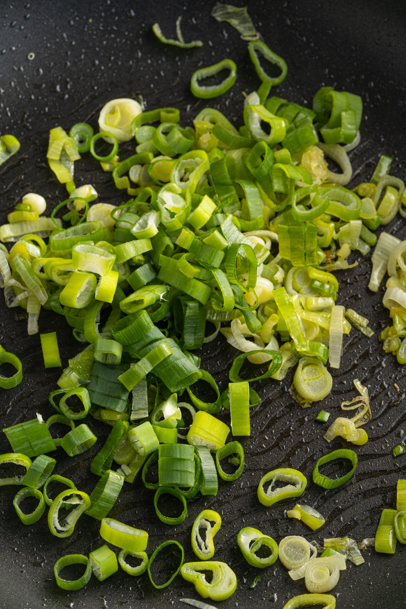 Picture of chopped green onions in a pan with olive oil.