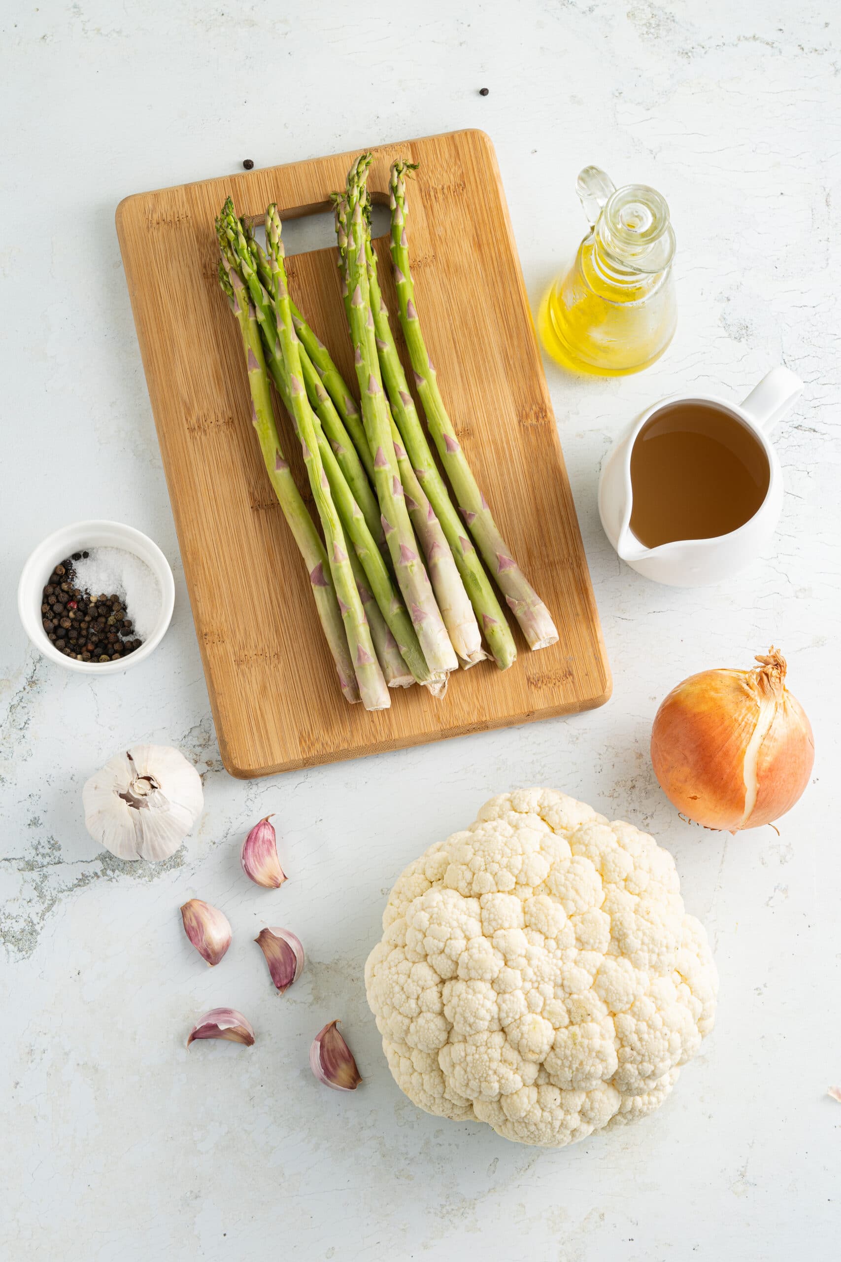 Ingredients on a white background or small white pitchers or white bowls and asparagus spears on a wood board.