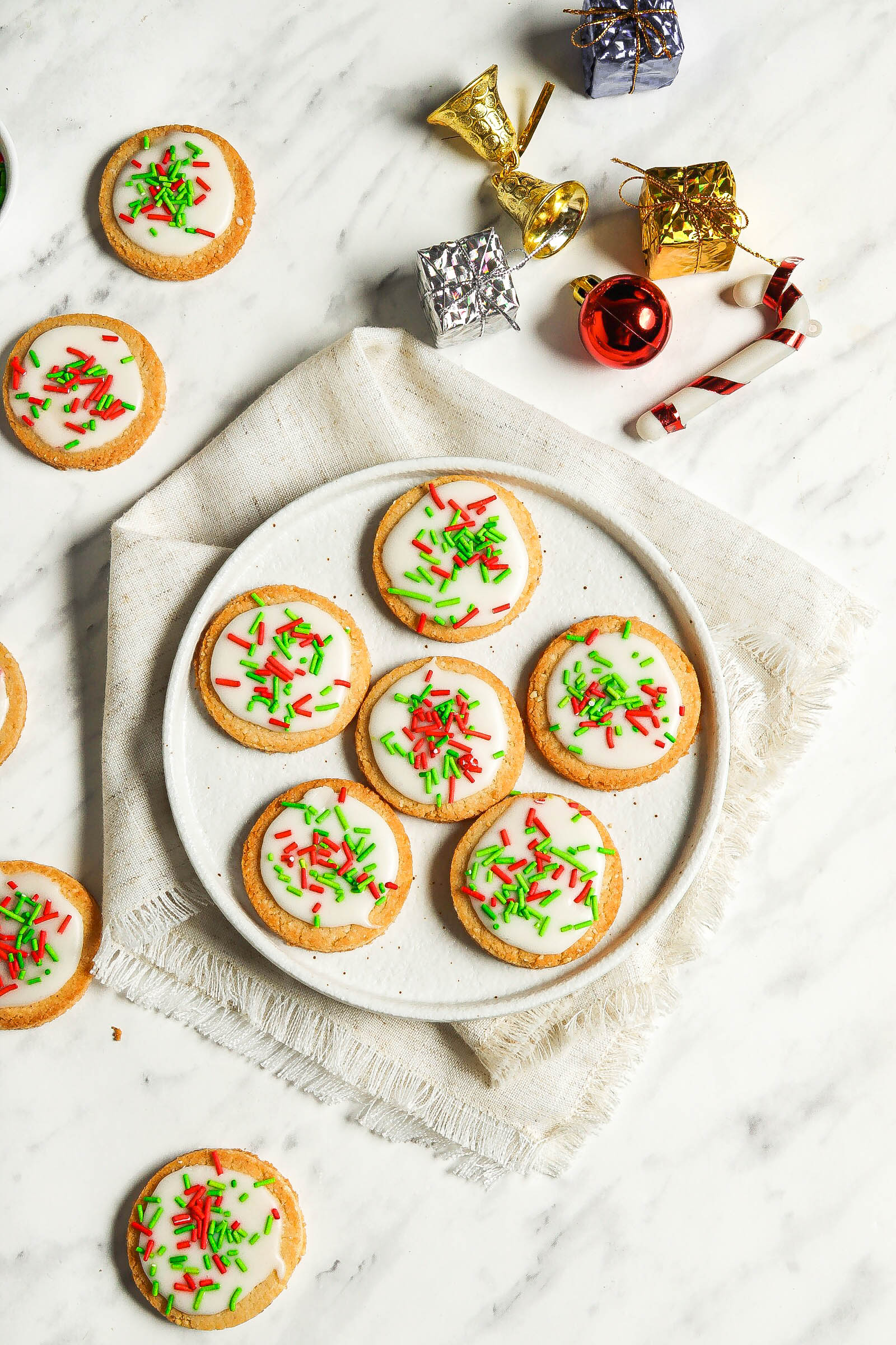 Overhead shot of cookies with red and green sprinkles on a white round plate.