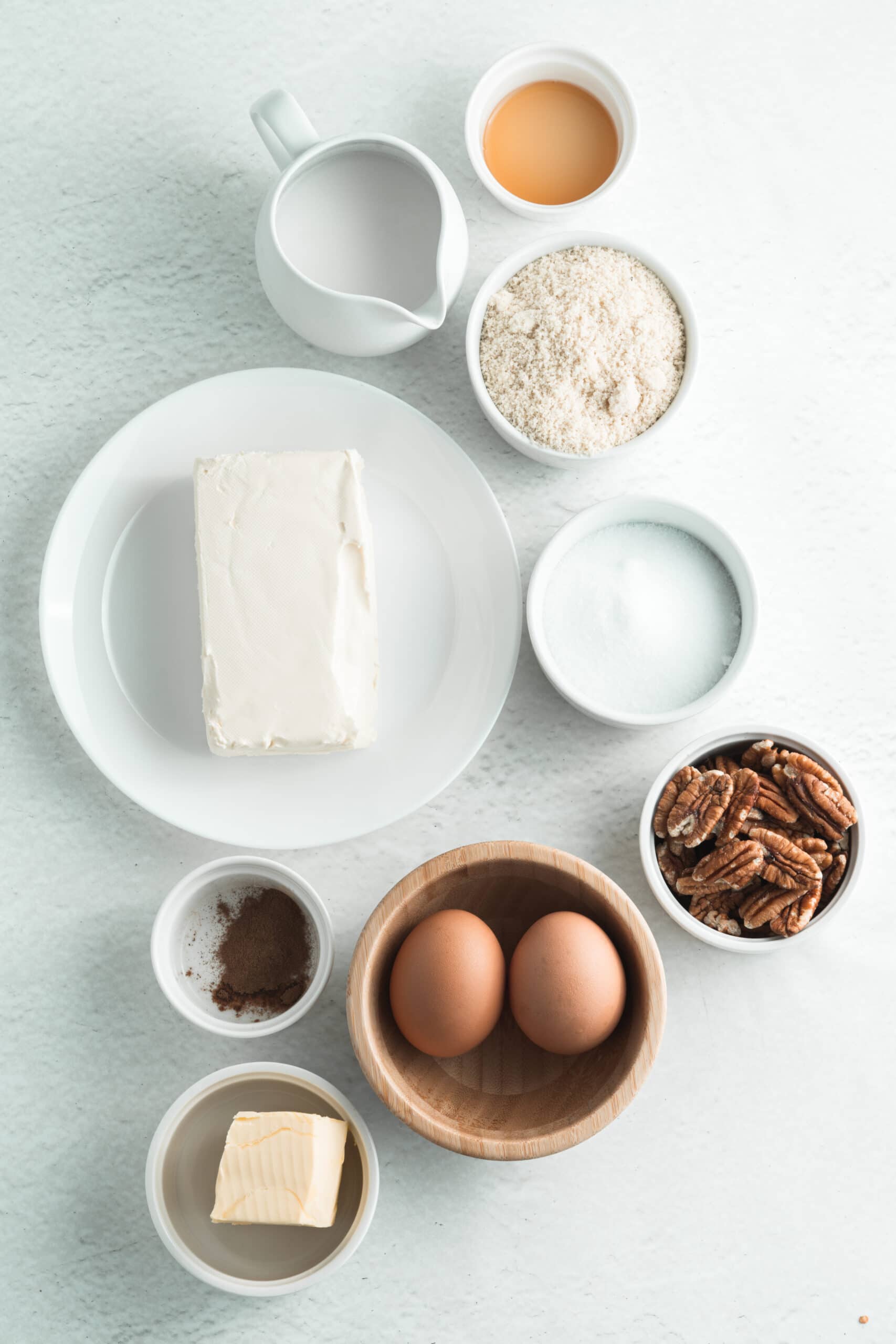 Overhead picture of separate ingredients on a white background in small white bowls, small white plate and a small white pitcher,