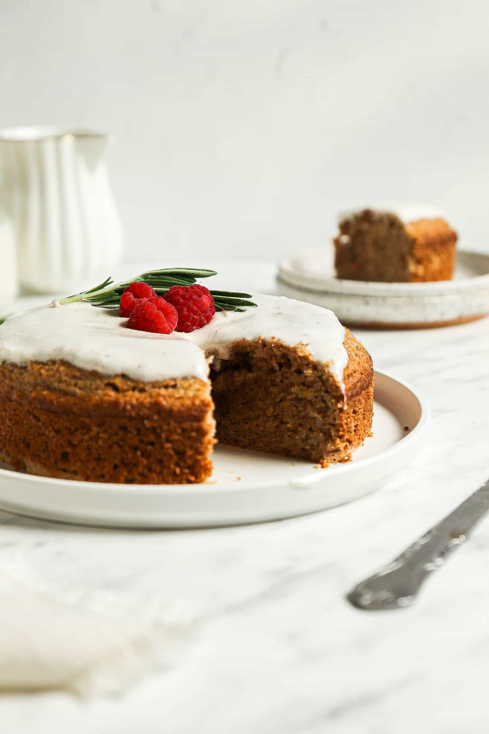 Picture of gingerbread cake on a white plate with berries on top and a slice cut out.