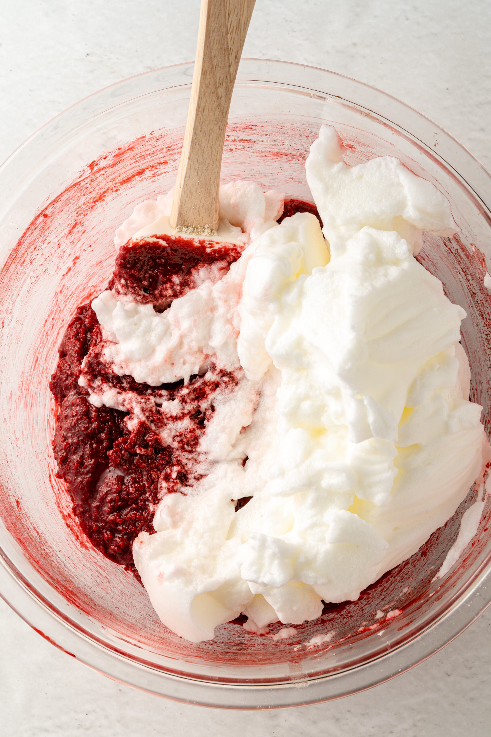 Whipped egg whites folded into red mixture in large mixing bowl.