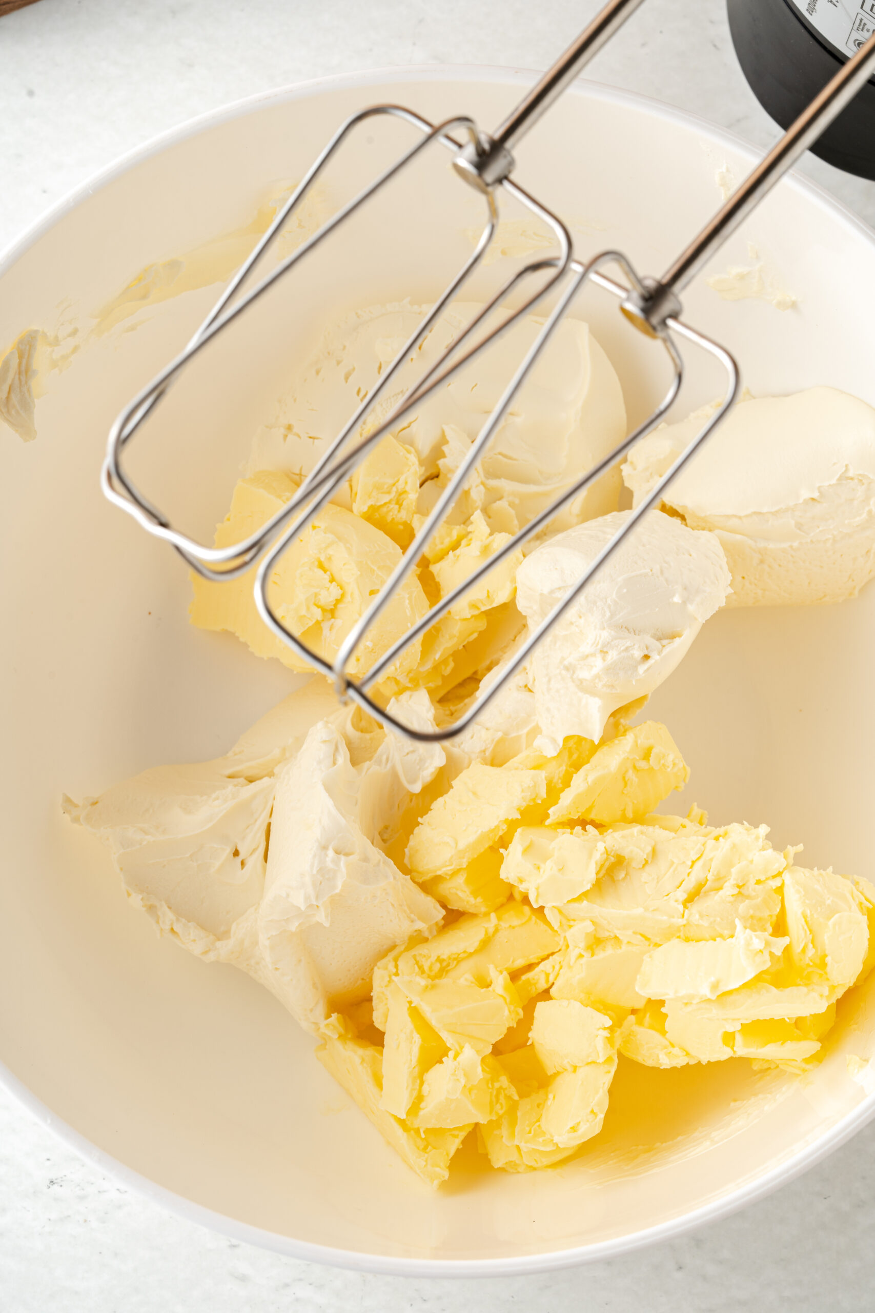 Butter in a mixing bowl with electric mixer in it.