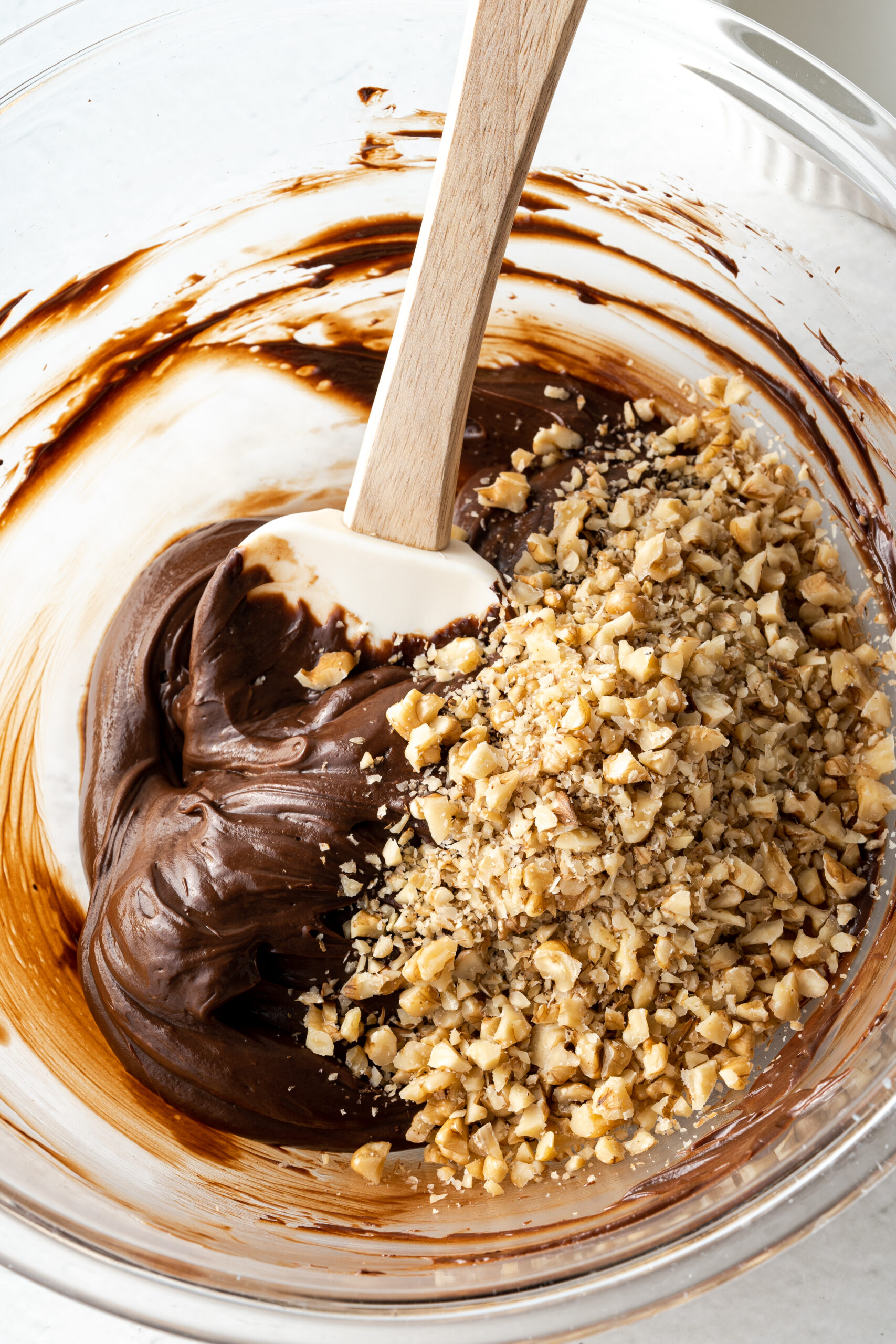 Chocolate mixture and walnuts in a glass mixing bowl.
