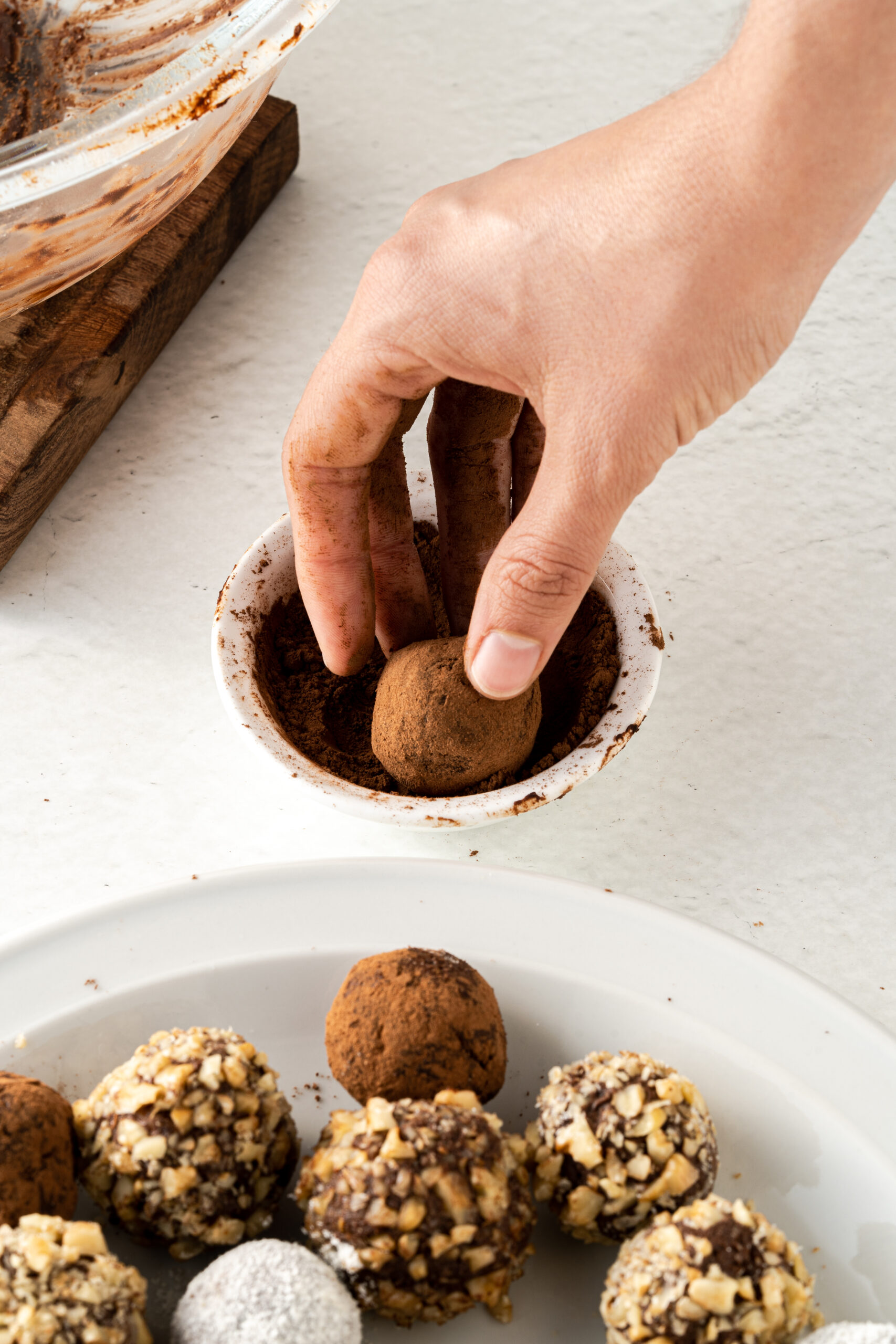 Hand rolling chocolate truffle in a cacao mixture.
