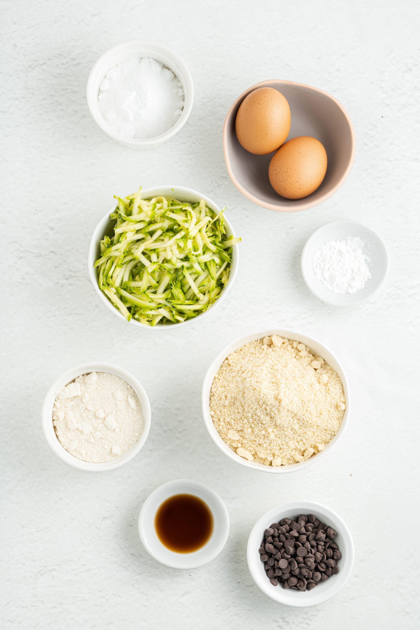 Ingredients for chocolate chip zucchini cookies in small white bowls.