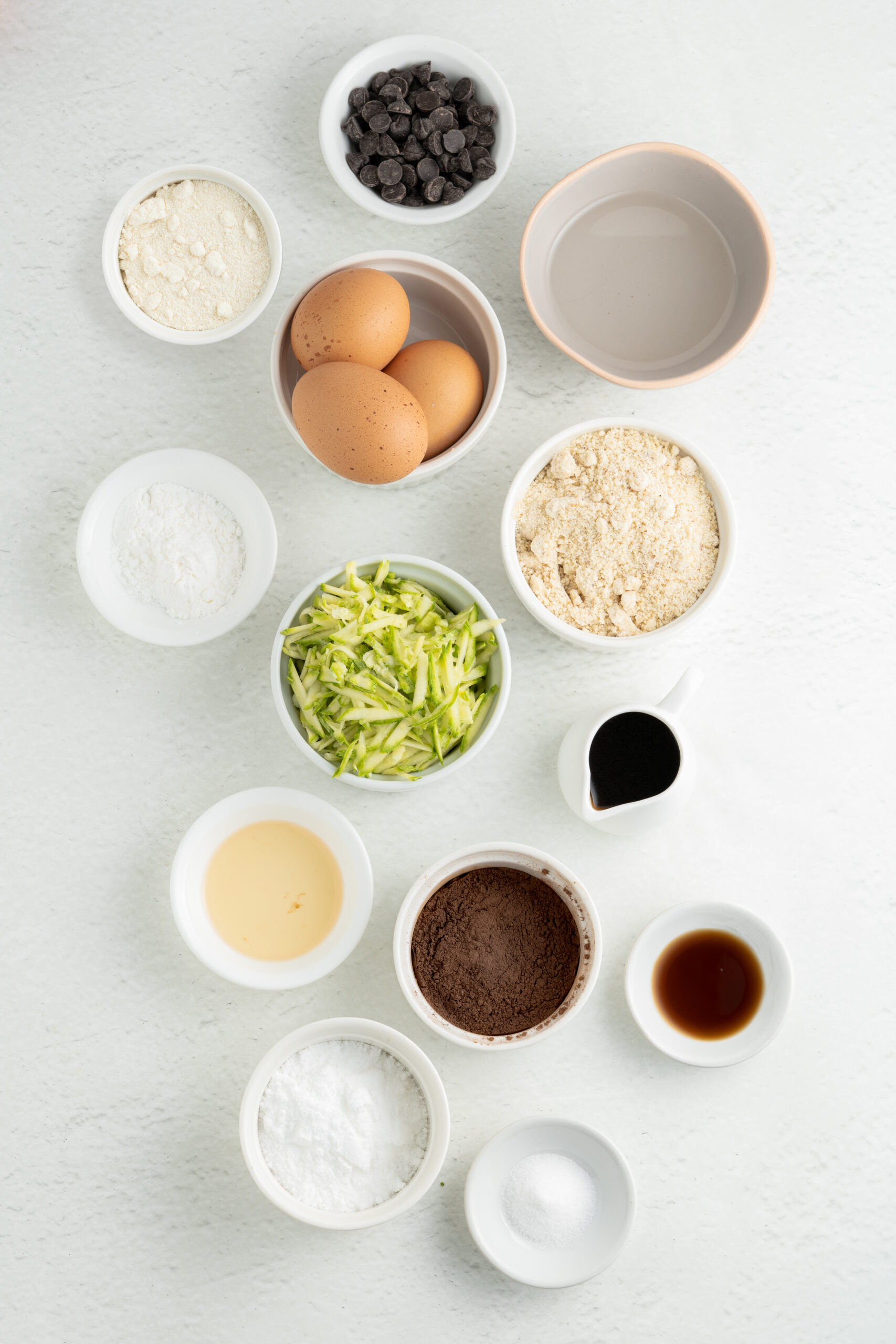 ingredients for chocolate zucchini bread in small white bowls.