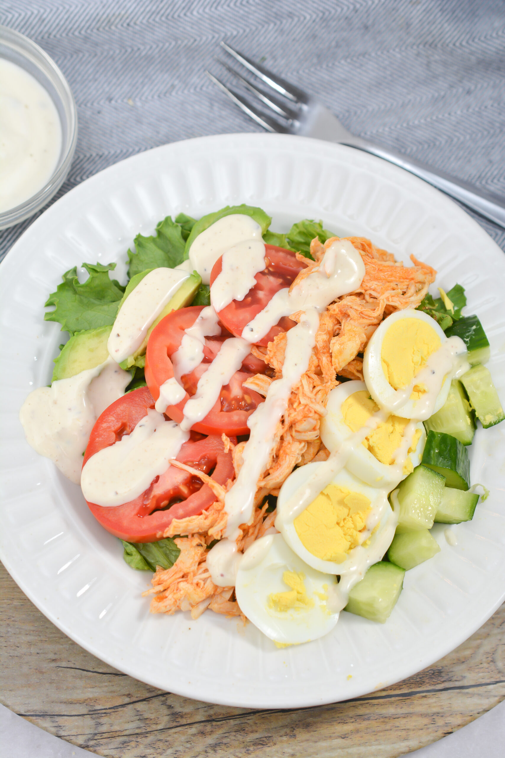 Finished buffalo chicken Cobb salad on a white plate.