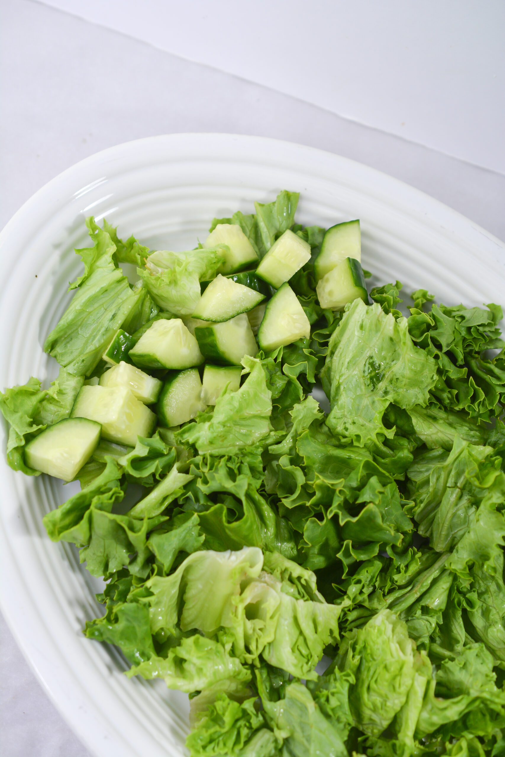 Chopped lettuce and cucumbers on a plate.
