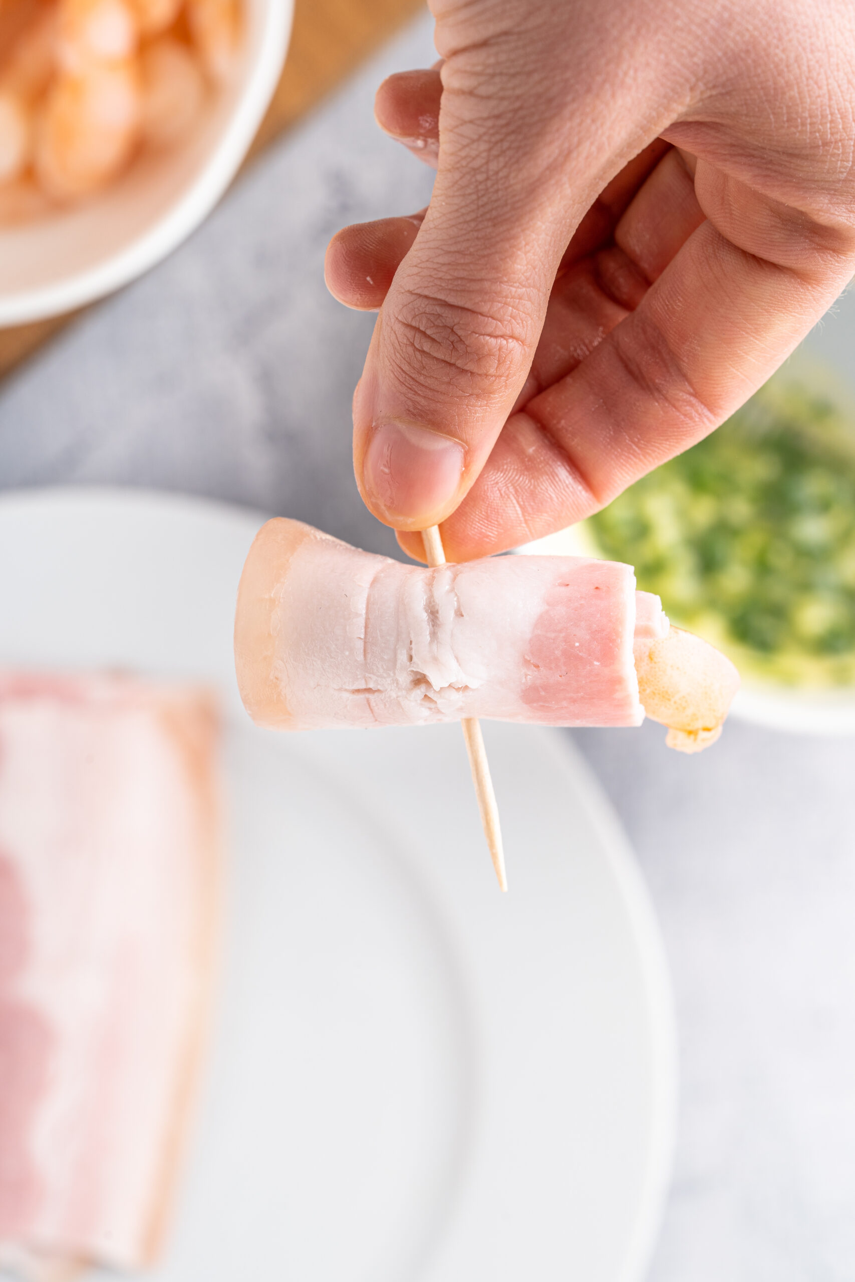 Placing toothpick in bacon shrimp.