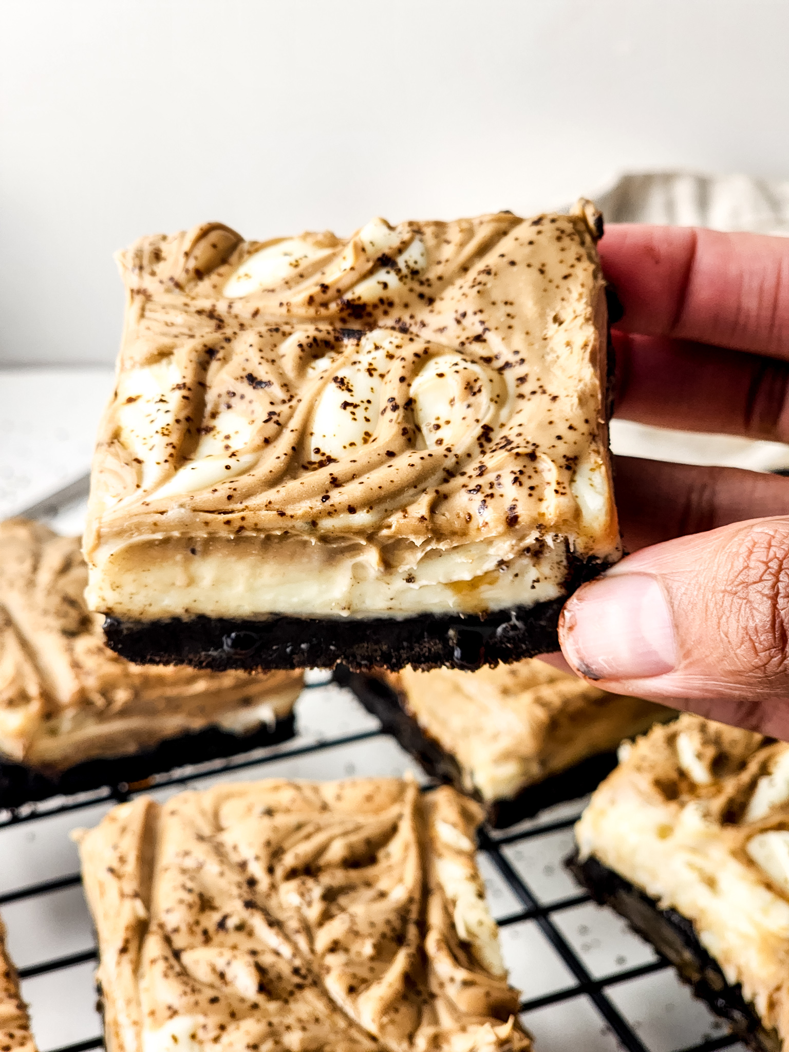 Hand holding finished Cheesecake Bars.